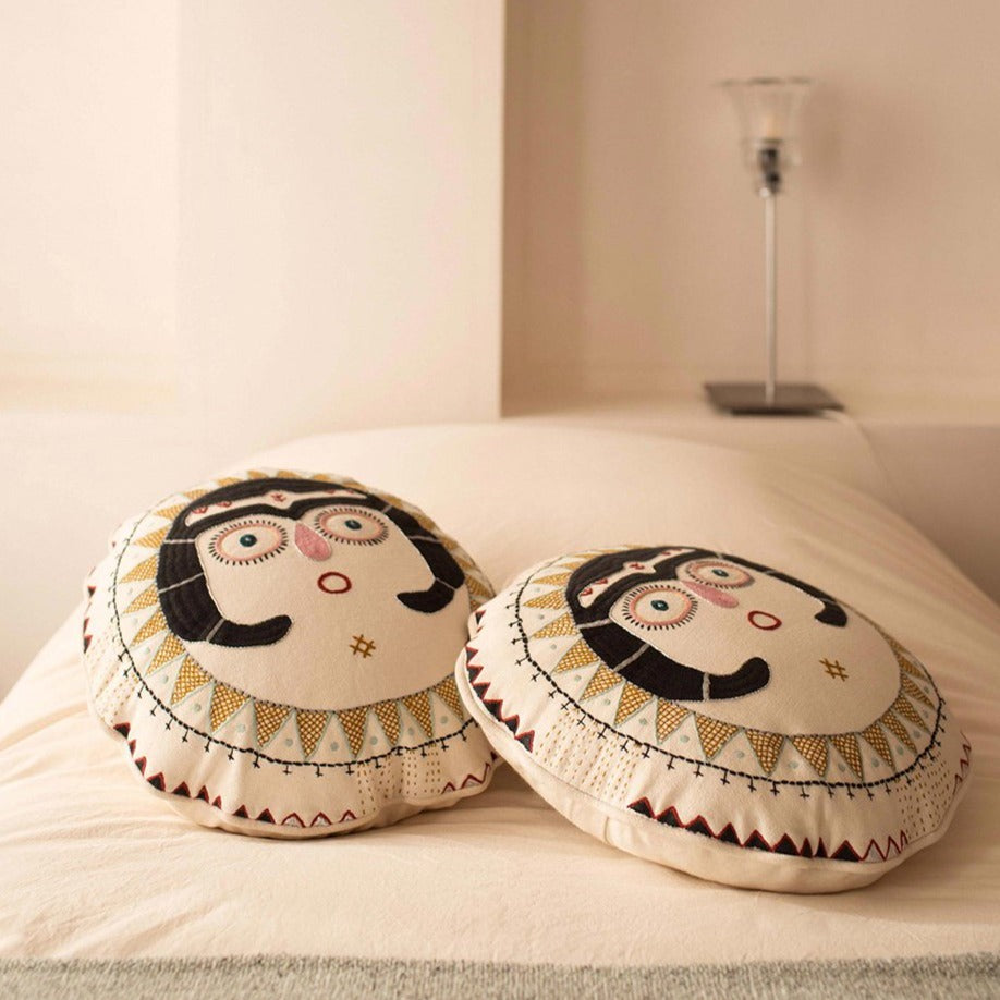 Two charcoal Sun Lady cushions on top of a bed