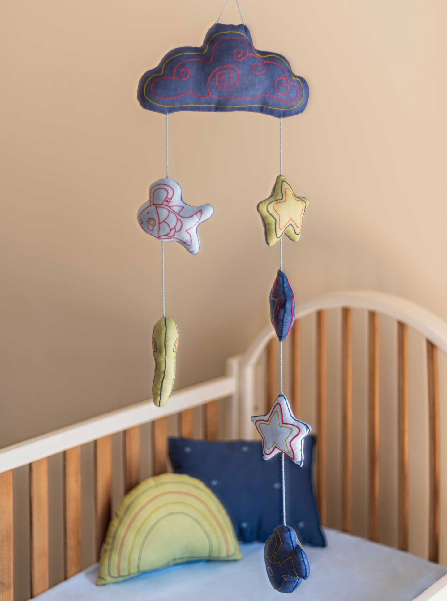 Blue Lucky Charm baby mobile hanging from the ceiling o top of a baby crib