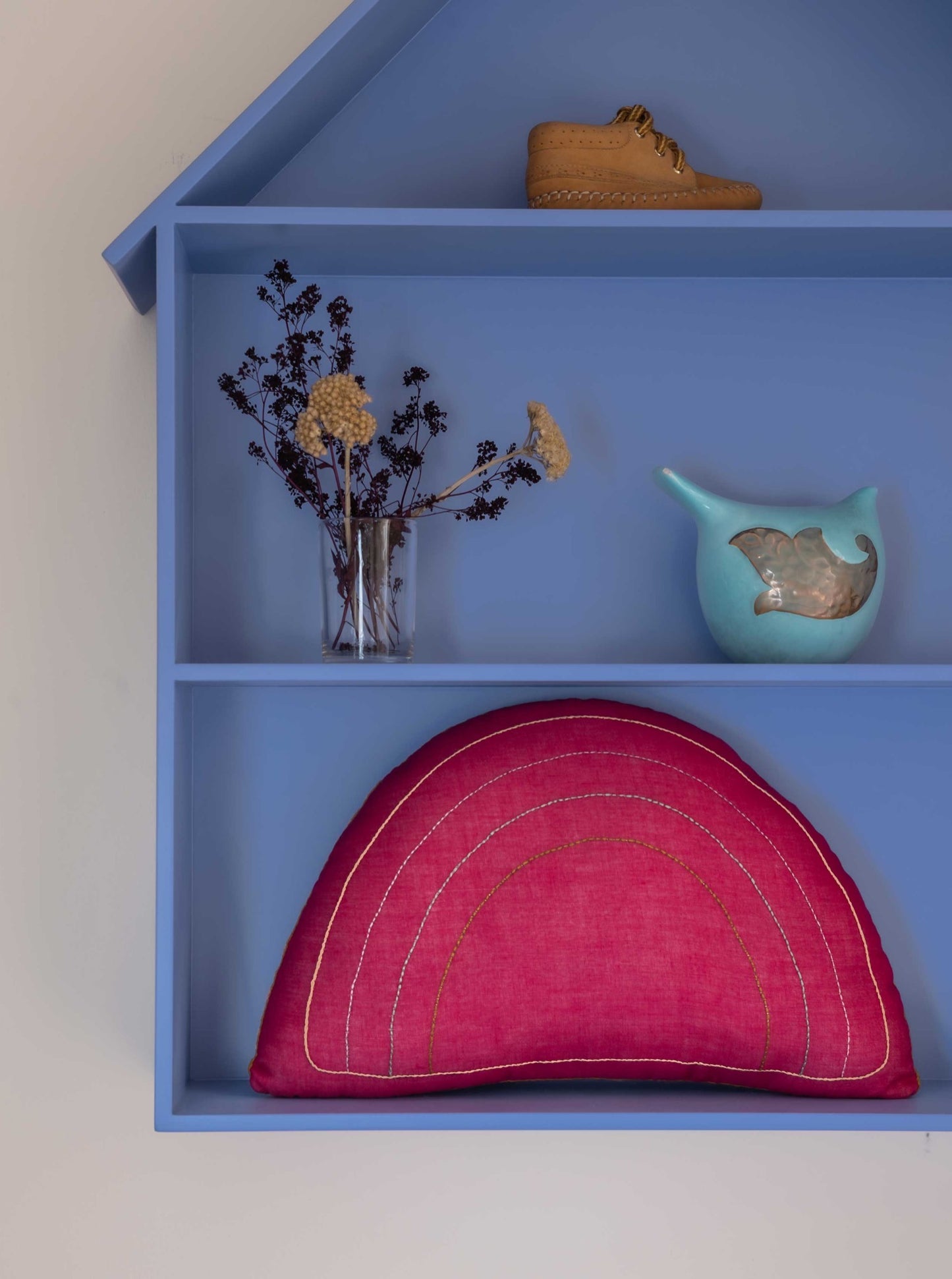 Fuchsia Rainbow decorative kids cushion with embroidery inside a blue decorative shelf
