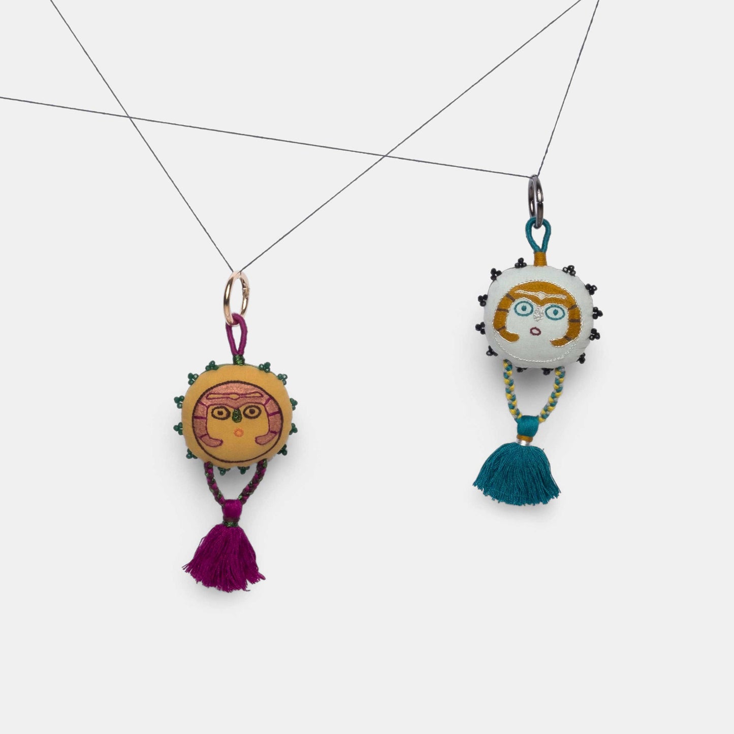 Mustard and Silver Gray Sun Lady charms hanging from a thread