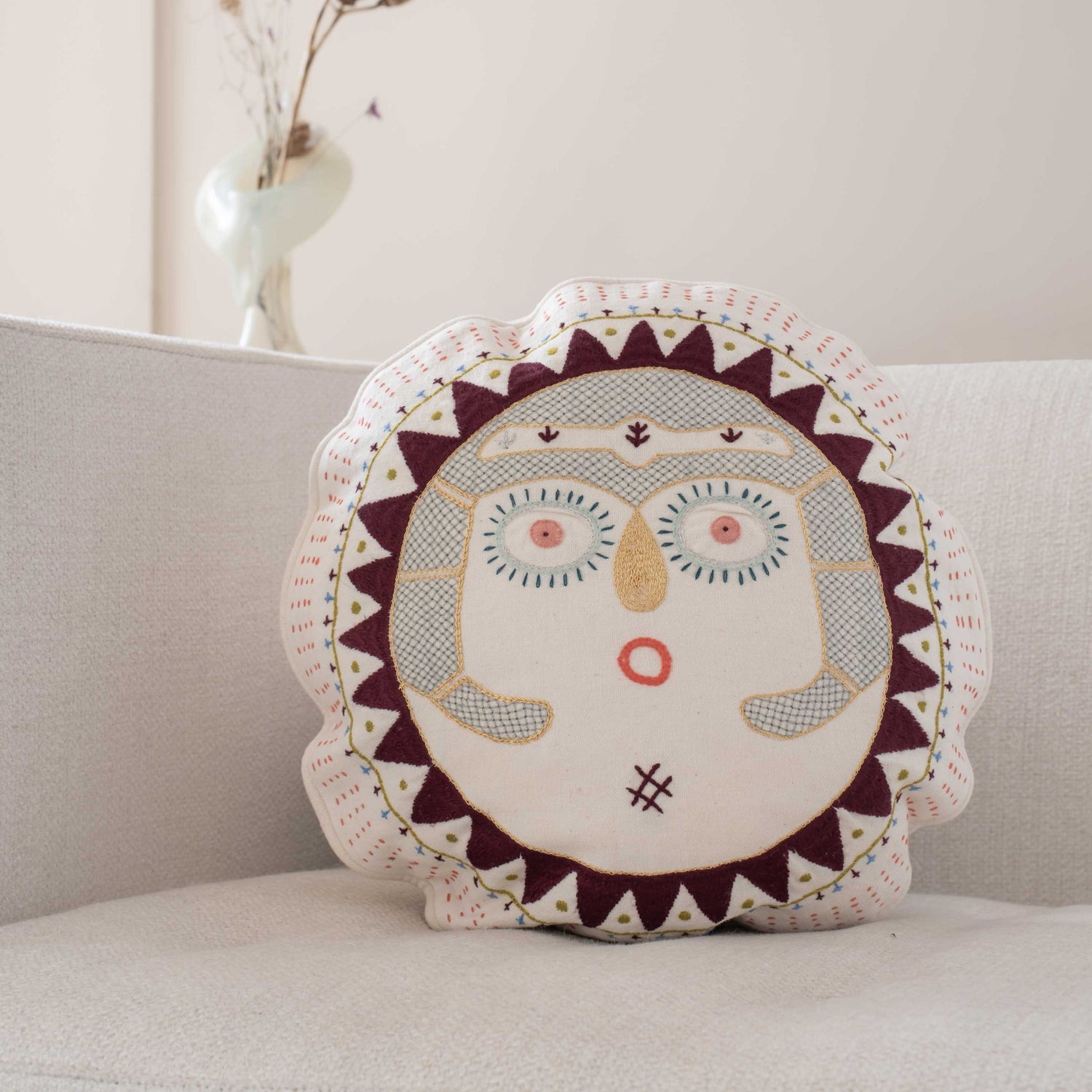 Beetroot round Sun Lady cushion placed on a sofa