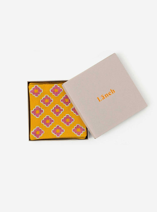 Mustard Apadana coaster set with pink flower embroidery inside a light grey Laneh box