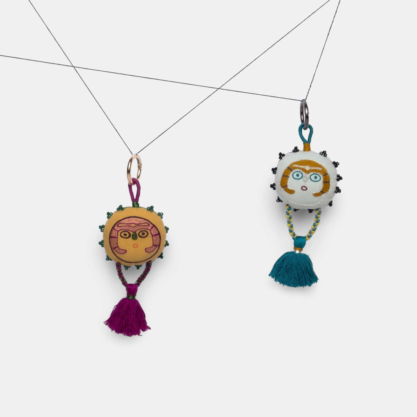 Mustard and Silver Sky Sun Lady charms hanging from a thread