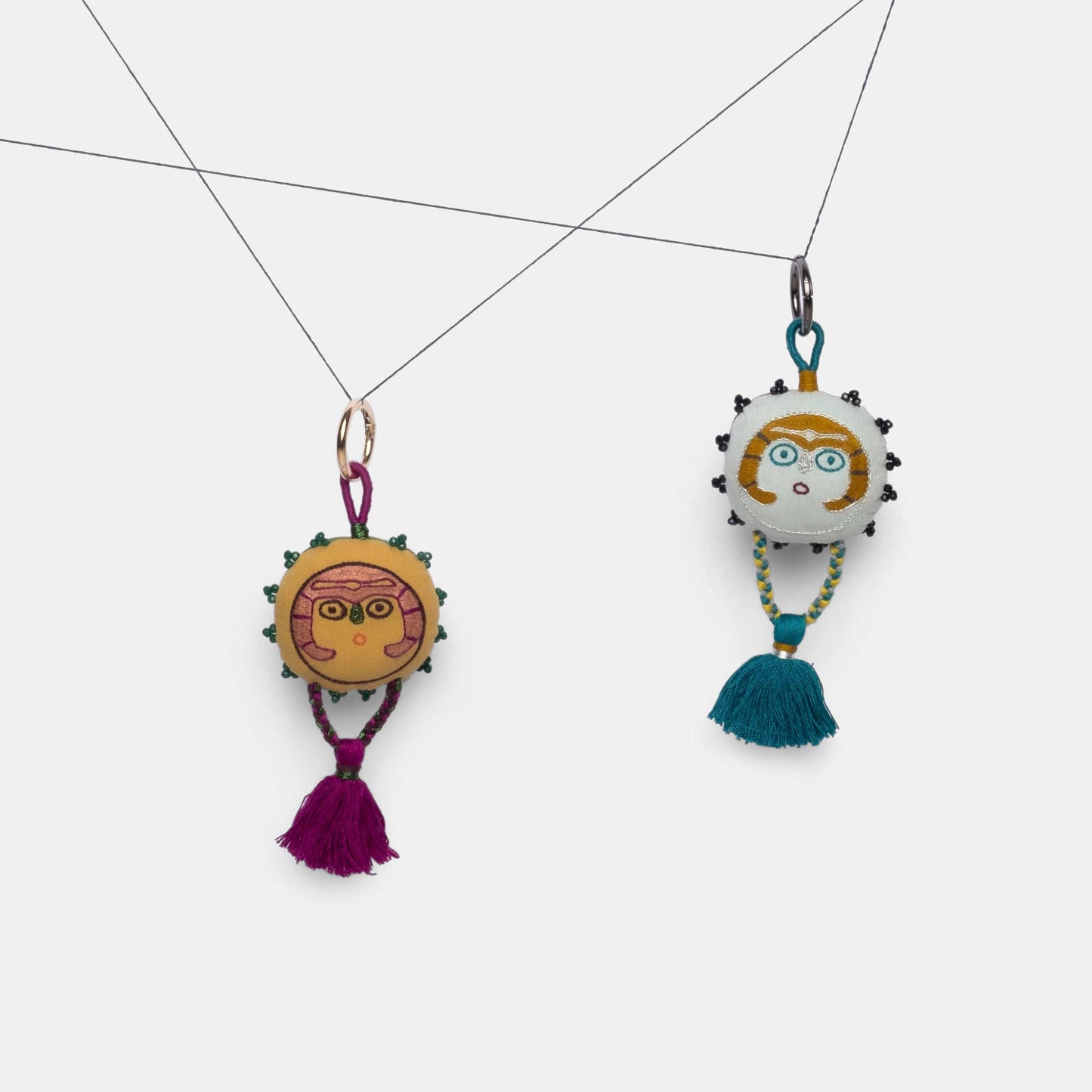 Mustard and Silver Sky Sun Lady charms hanging from a thread